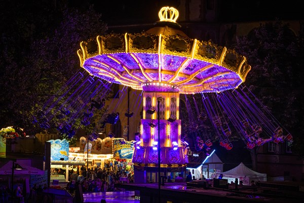 The colourful lights of the carousel at the Mainfest glow in the evening. The Mainfest on the Mainkai