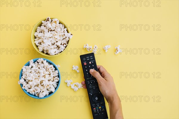 Crop hand remote control near popcorn
