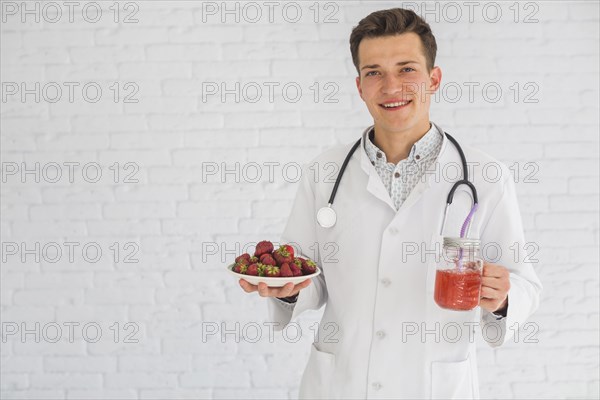 Portrait male doctor holding strawberry fruits smoothie