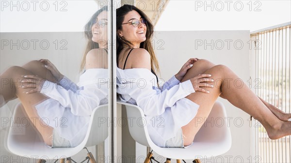 Smiling young woman sitting white chair balcony