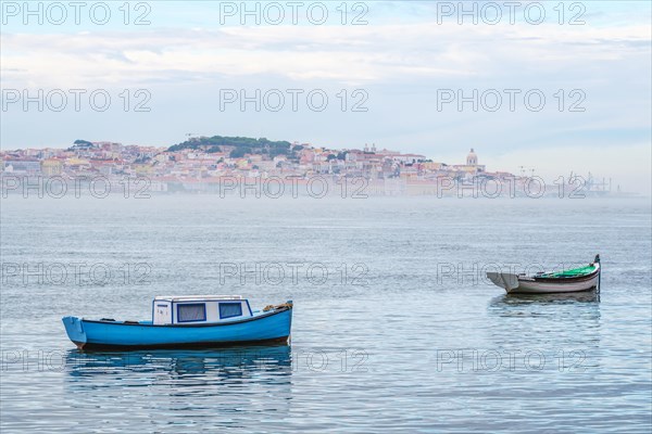 Fishing boats in Tagus river on misty morning with Lisbon in background with miSt Lisbon