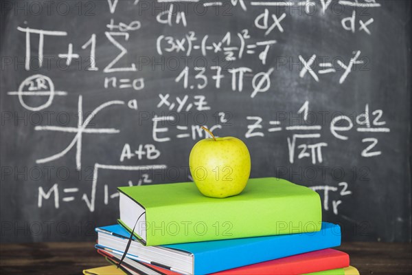 Apple books pile near chalkboard