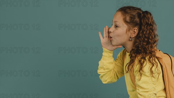 School girl with yellow shirt telling secret