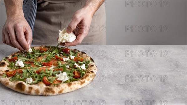 Man putting mozzarella baked pizza dough with smoked salmon slices
