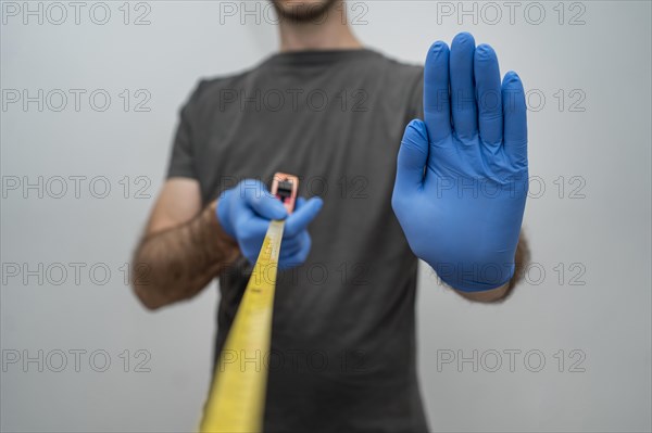 Man with gloves holding tape measurer social distancing