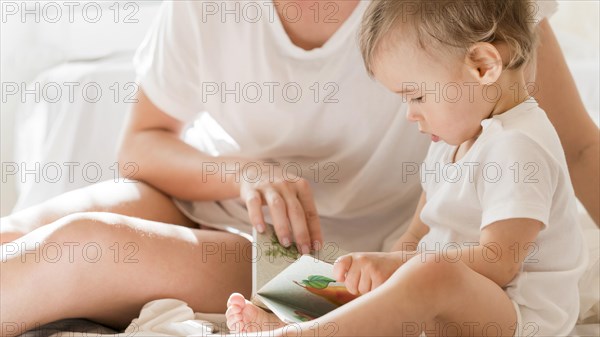 Mom baby sitting bed with book