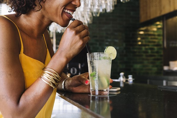 Smiling young woman drinking mojito bar counter restaurant