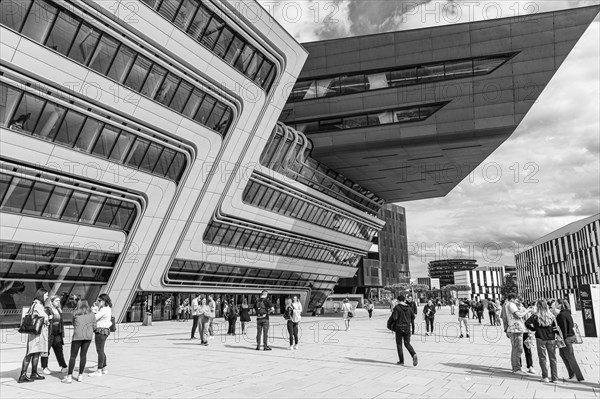 Students in front of a modern building on the campus of the University of Economics WU