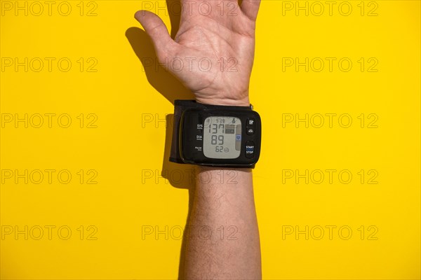 Blood pressure monitor on a man's trading joint against a yellow background