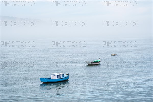 Boats in river on misty morning with background with heavy fog. Lisbon