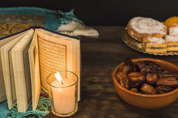 Dates pastry near burning candle opened book