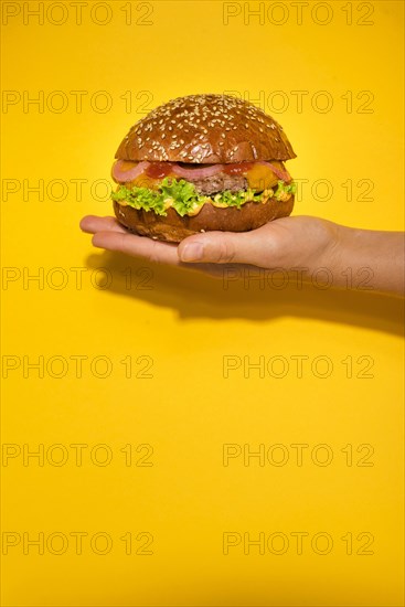 Hand holding classic beef burger with lettuce