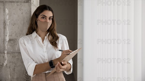 Front view businesswoman with mask clipboard