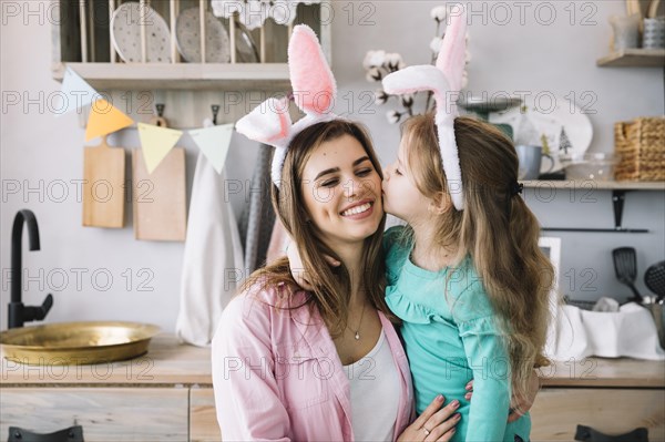 Cute girl bunny ears kissing mother cheek