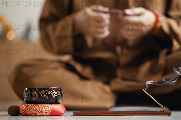 Front view defocused man meditating with beads singing bowl