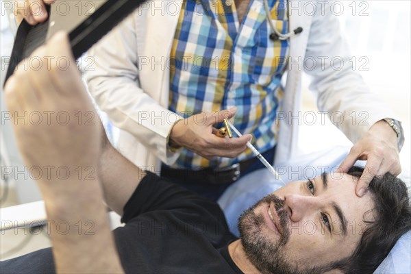 Latin man getting filler injections in aesthetic medical clinic