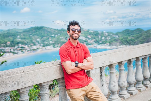 Handsome tourist man looking at the bay of San Juan del Sur. Portrait of smiling tourist in a viewpoint of a bay