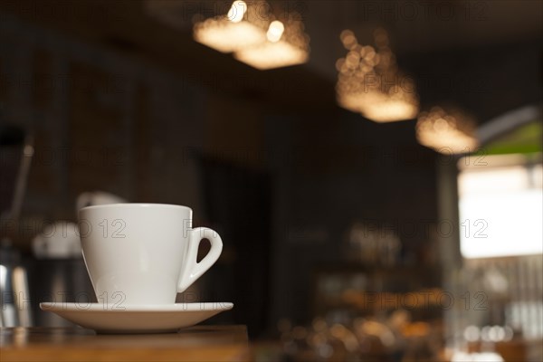 Cup coffee with saucer table with defocus cafe background