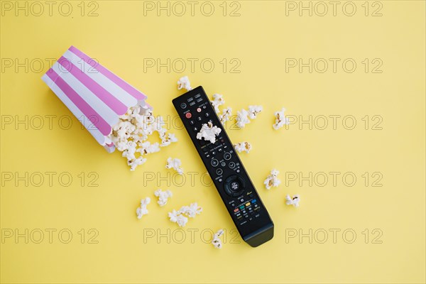 Tv remote control near spilled popcorn
