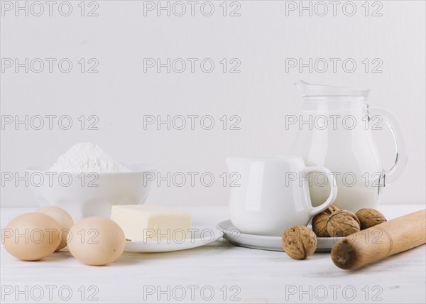 Flour milk eggs cheese rolling pin walnuts white backdrop making pie