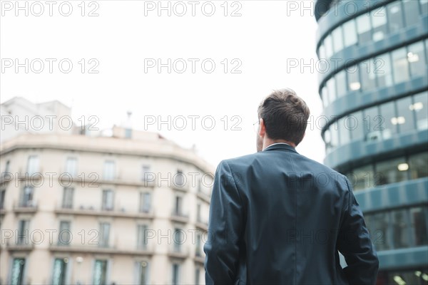 Rear view businessman looking corporate building city