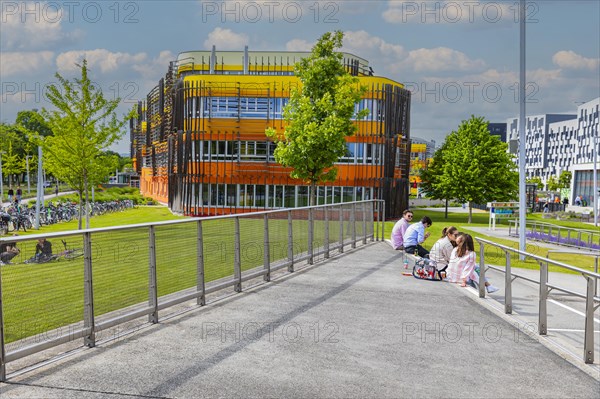 Students sitting in front of modern buildings on the campus of the University of Economics WU