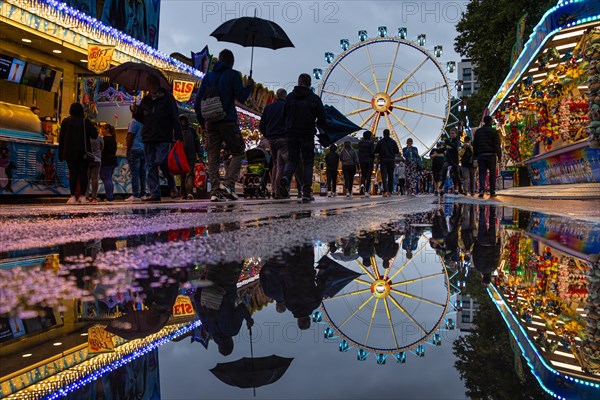 The colourful lights of the Mainfest are reflected in a puddle. The Mainfest on the Mainkai