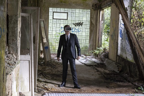 Man dressed in suit wearing VR glasses in a dilapidated office building