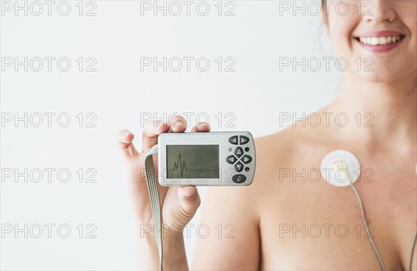 Woman with electrodes holding monitor with cardiogram