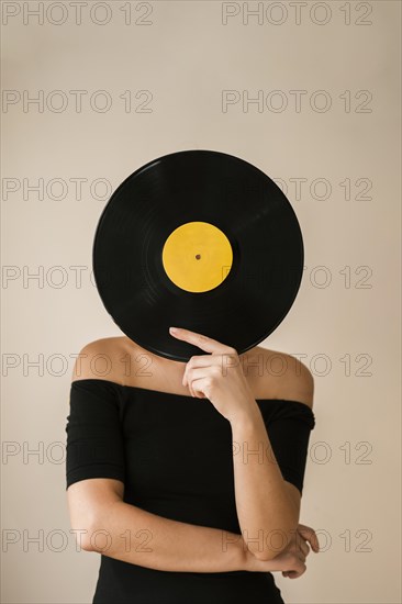 Young woman holding vinyl record her face