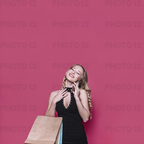 Cheerful blond woman with bags speaking phone