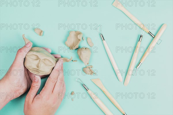 Close up sculptor artist creating sculpture face with clay colored background