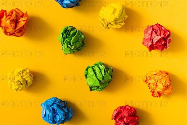 Colorful crumpled paper ball yellow background