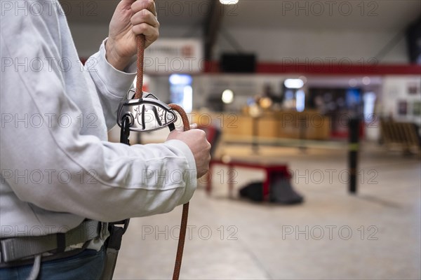 A person holding a rope for belaying in a climbing gym