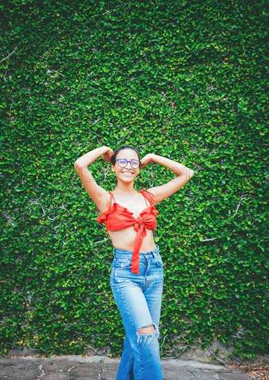 Portrait of attractive smiling latin girl on a wall of leaves. Portrait of young latin woman with leaves wall background