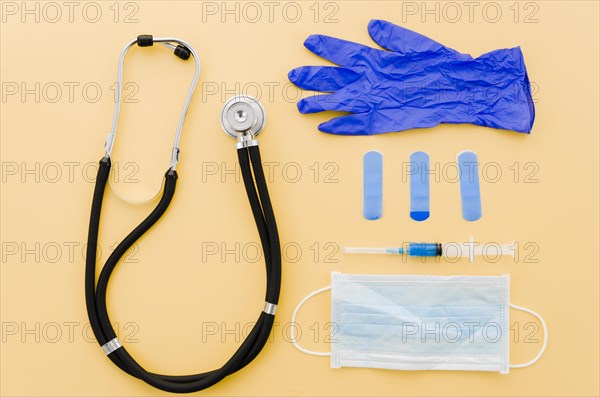 Stethoscope crumpled gloves bandages syringe surgical gloves yellow background