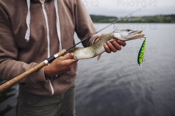 Close up man holding freshly caught fish with lure