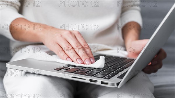 Hands disinfecting laptop surface