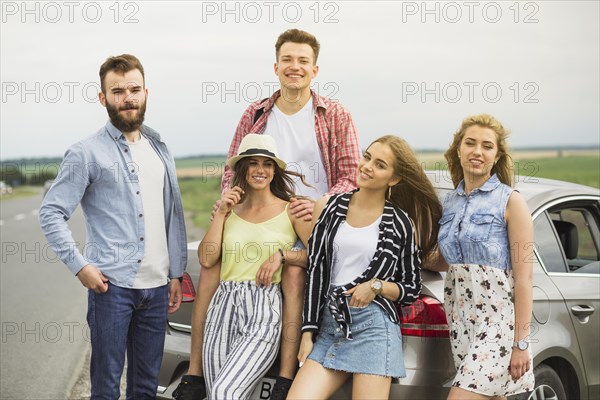 Portrait smiling young friends standing near car