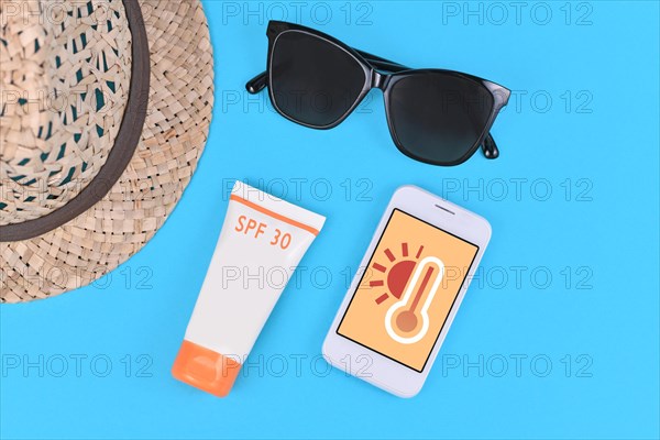 Concept for hot temperatures in summer with mobile phone showing weather forecast surrounded by sun glasses