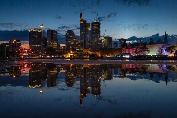 The colourful lights of the Mainfest are reflected in a puddle. The Mainfest on the Mainkai