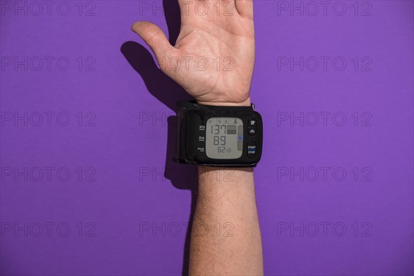 Blood pressure monitor on a man's trading joint against a violet background