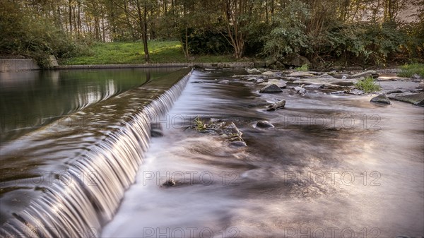 Mountain river waterfall. Beautiful natural background of stones and water. Long exposure. Visible river bank in the rays of the setting sun. Copy space