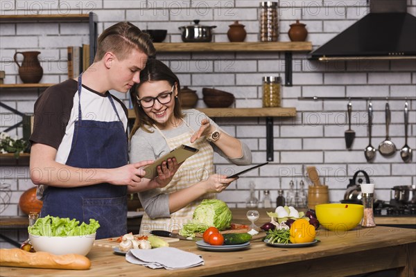 Couple surfing tablet cooking together