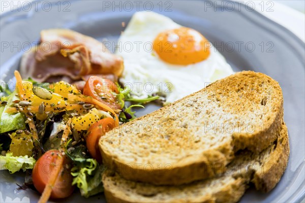 Close up toast fried eggs salad bacon served ceramic plate