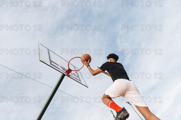 Cool sporty man throwing basketball into hoop