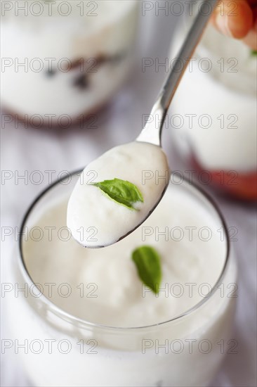 Hand holding spoon with yogurt