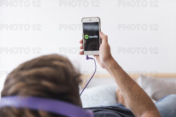 Young man holding smartphone with spotify app