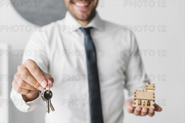 Crop real estate agent with keys house