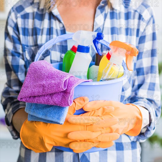 Mid section woman holding cleaning equipments blue bucket